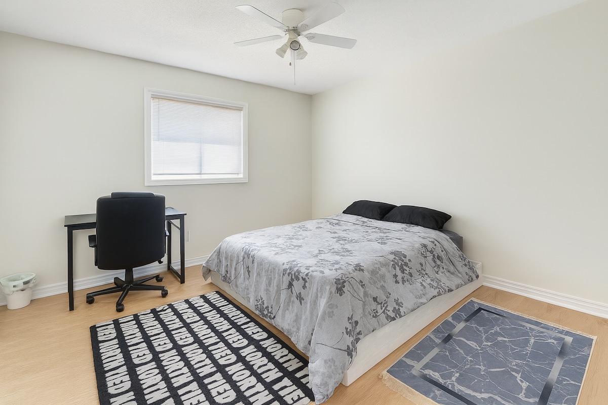 غرفة نوم مشرقة وبسيطة تتميز بسرير مريح ومكتب عمل ومروحة سقف. مثالي لقضاء ليلة هادئة أو إعداد مثالي للعمل من المنزل.