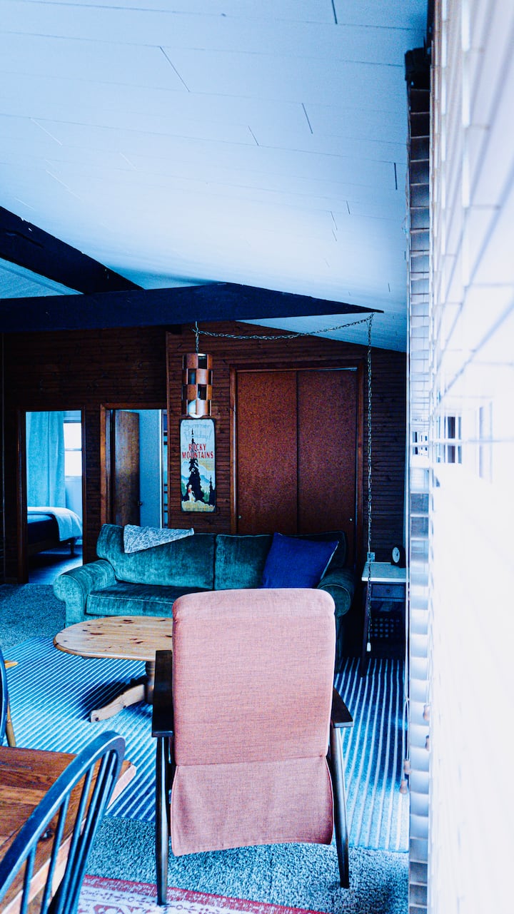 Una cómoda sala de estar con muebles suaves y paredes de madera cálida, perfecta para leer, conversar o relajarse después de un día al aire libre. El diseño abierto mantiene todo conectado y acogedor.