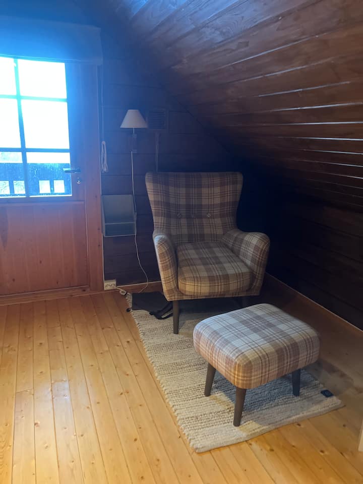 Habitación en el ático con TV, sillón y sofá cama. 