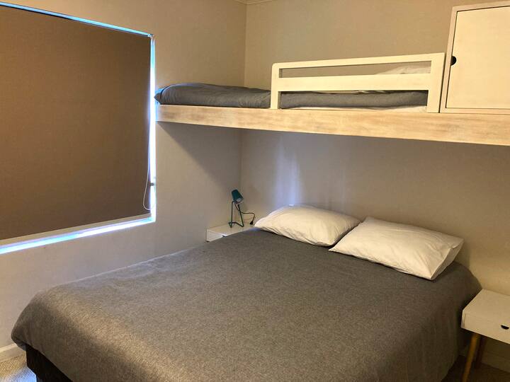 Familieværelset. Indeholder en komfortabel dobbeltseng nedenunder og en enkelt køjeseng ovenpå (med sikkerhedsskinne). Ideel til tre gæster. Enkelt og funktionelt design med mørklægning for den bedste søvn. Den optimerede bolig, du har brug for!