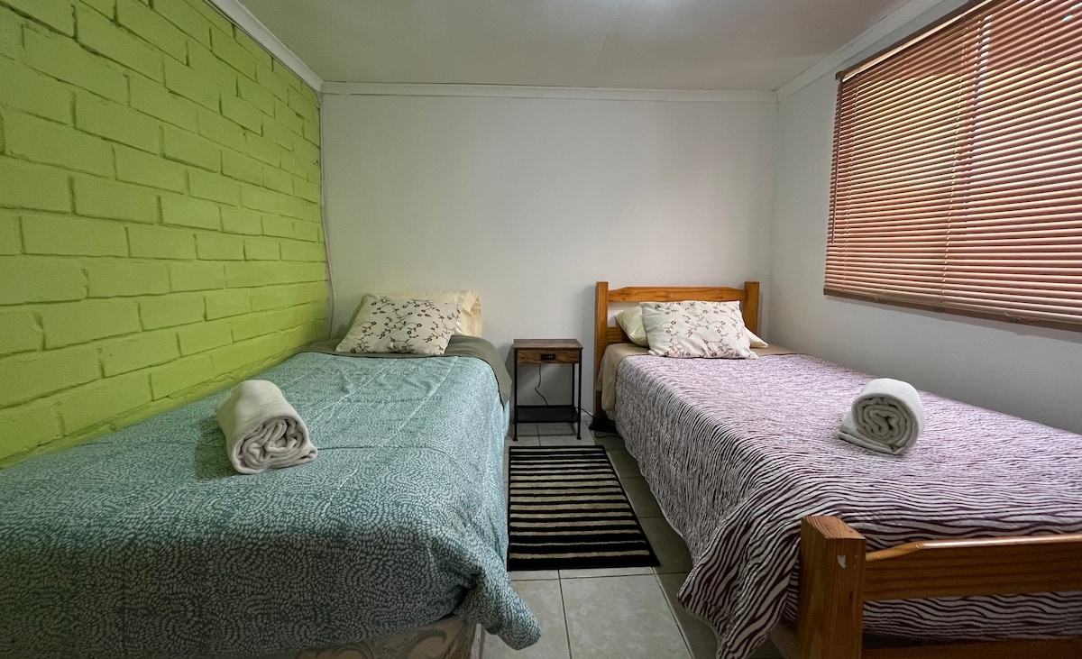 חדר עם 2 מיטות יחיד, הכולל מנורות USB, שידת לילה ומתלה בגדים.