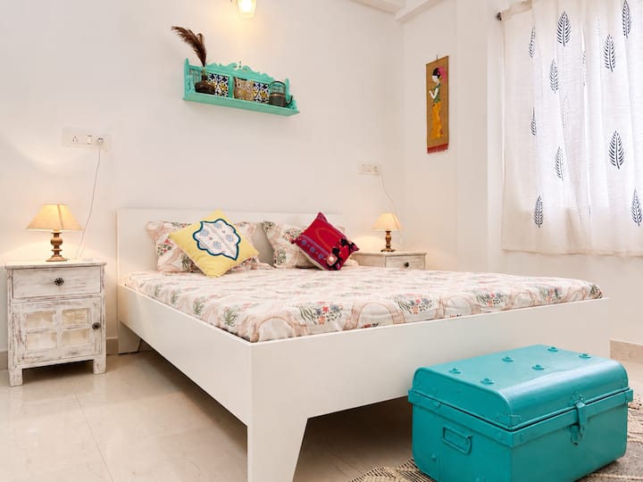 Grande chambre avec lit double et mobilier vintage. La chambre a une salle de bain attenante et un balcon