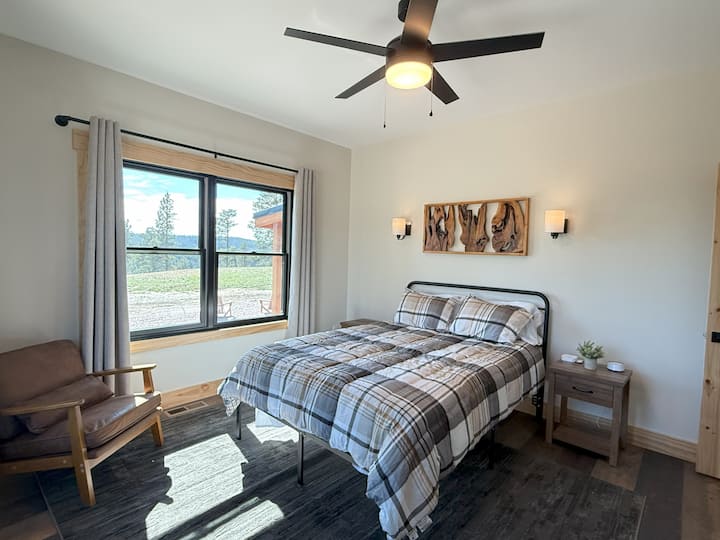 Táto svetlá, príjemná spálňa má manželskú posteľ, moderný rustikálny dekor a veľké okná s pokojným výhľadom na les. Jemné svetlo a jednoduché pohodlie z neho robia relaxačný priestor na odpočinok po dni strávenom v Black Hills.