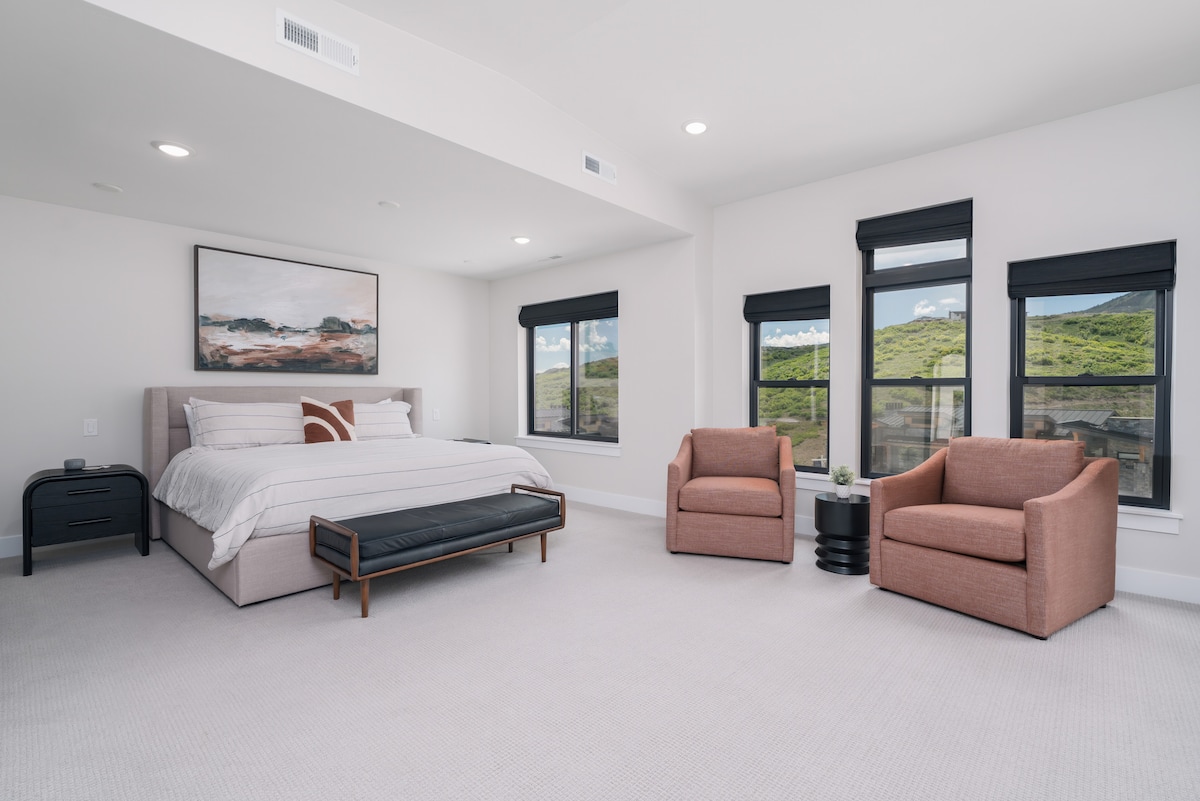 Primaire slaapkamer met een kingsize bed, zithoek en terras met loungestoelen