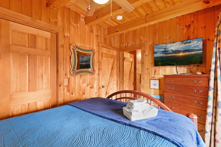 A relaxing bedroom retreat with soft lighting and peaceful cabin style. It’s ideal for couples or solo travelers looking for comfort, privacy, and a quiet place to recharge during their mountain getaway.