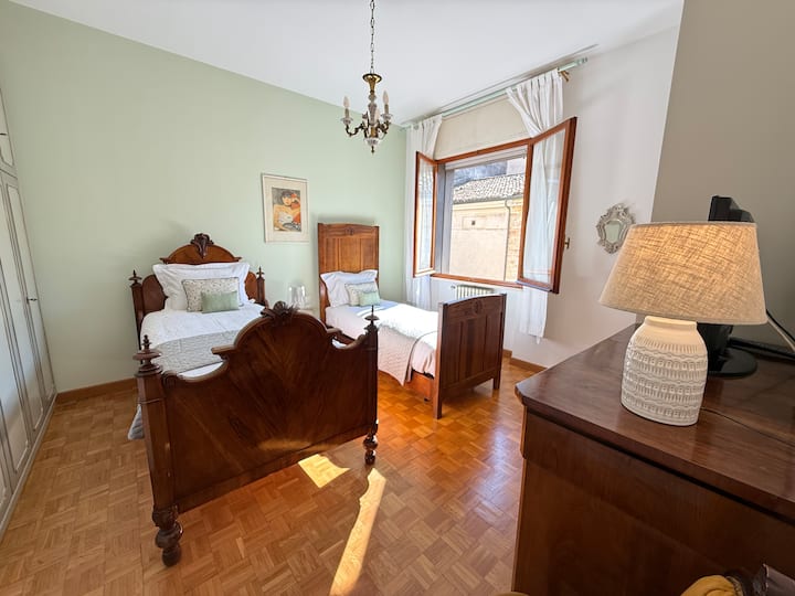 Habitación compuesta por dos camas individuales, una de las cuales es más ancha y larga.
