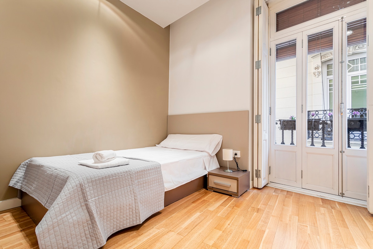 חדר שינה אלגנטי ובהיר עם מיטת יחיד גדולה, מצעים איכותיים וגישה למרפסת. מעוצב בגוונים חמים ופרטים מודרניים, הוא מציע אווירה רגועה אידיאלית למנוחה וליהנות משהייה נוחה.