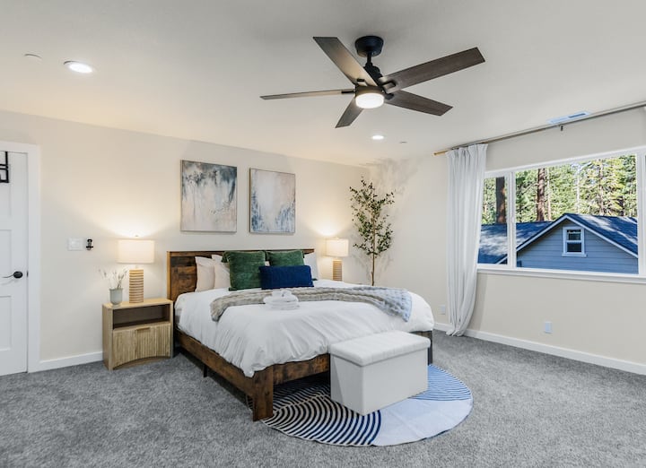 King bedroom with two nightstands, soft lamps, plush comforter, and elegant French drape curtains for a restful, stylish stay.