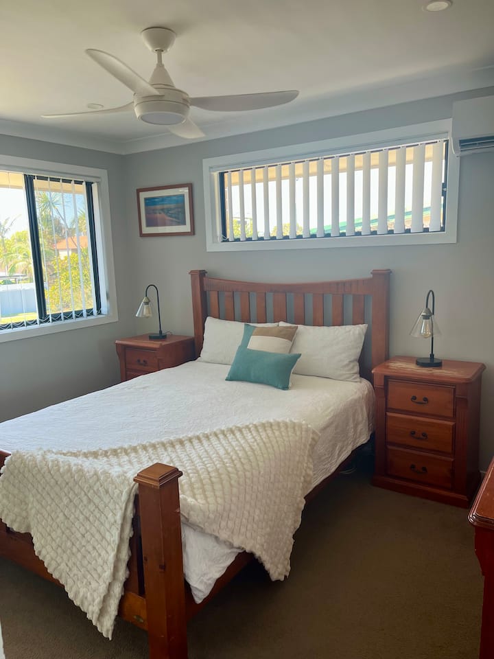 ห้องนอนหลักมีเตียงควีนไซส์ปูด้วยผ้าปูที่นอนสีขาวสะอาด พร้อมโต๊ะข้างเตียง พื้นที่เก็บของ และตู้เสื้อผ้าเพื่อให้คุณแกะกระเป๋าและจัดวางได้อย่างเต็มที่