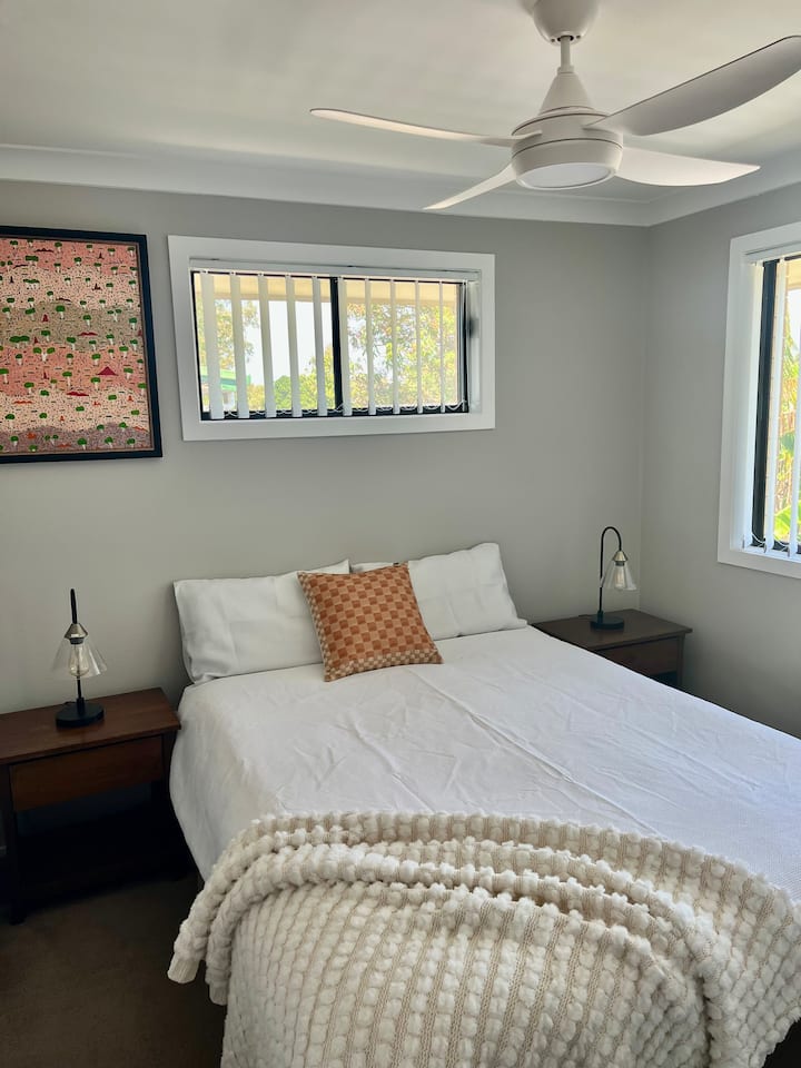 ห้องนอนมีเตียงควีนไซส์ปูด้วยผ้าปูที่นอนสีขาวสะอาด มีโต๊ะข้างเตียง พื้นที่เก็บของ และตู้เสื้อผ้าให้คุณแกะกระเป๋าและจัดวางได้เต็มที่