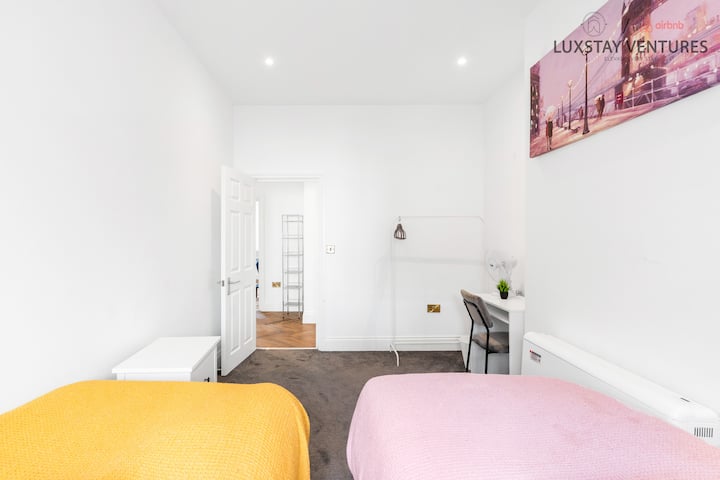 Een gezellige hoek voor rust en productiviteit, met twee eenpersoonsbedden en een grijs tapijt.