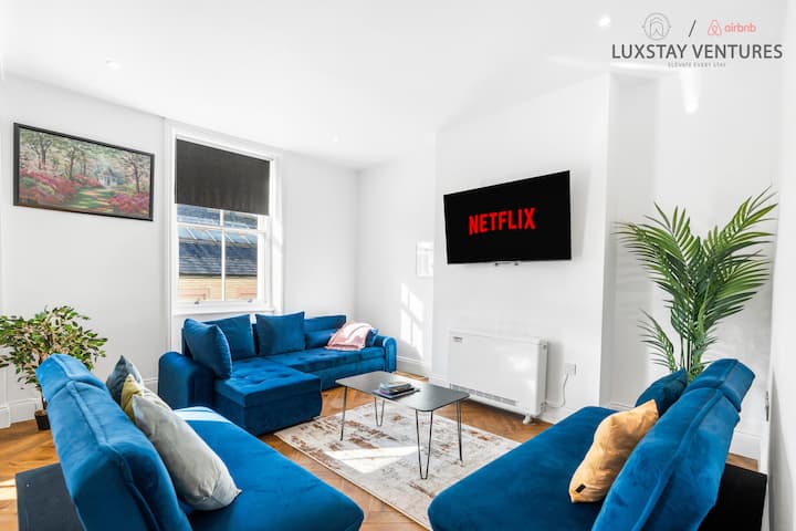 Lichte, stijlvolle woonkamer met houten vloeren, gezellige blauwe banken en je favoriete shows op Netflix