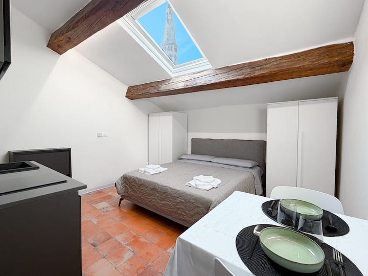 Dormitorio con Velux con vistas a la torre Ghilandina y un gran baño privado en la habitación. Equipado con cocina totalmente equipada, nevera, aire acondicionado, armarios grandes, entrada independiente y cama doble y Smart TV 4K con conexión a Internet.