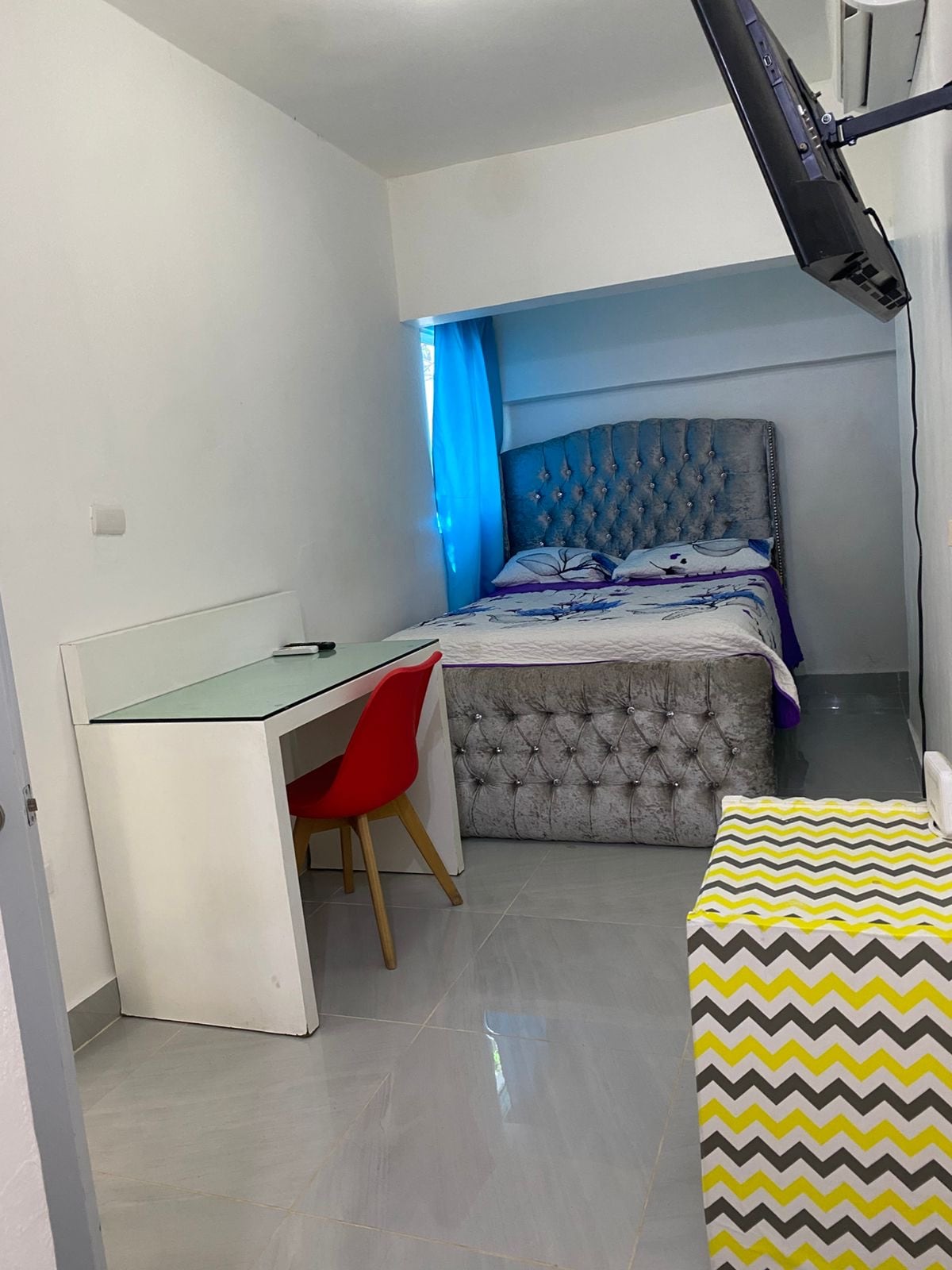 Двойно легло с табла с възглавници, бюро и стол за работа или учене.