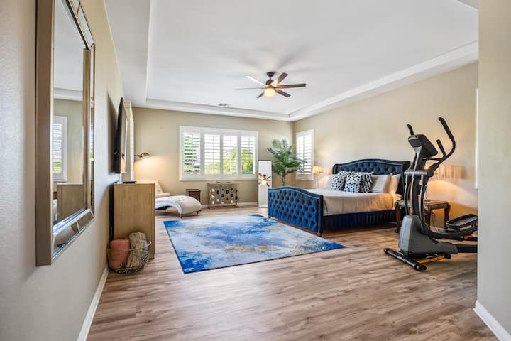 Una espaciosa suite principal con una lujosa cama azul, una acogedora sala de estar y equipo de fitness en la habitación