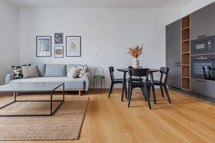 Sehemu ya kuishi angavu na ya kisasa iliyo na sofa ya kustarehesha, eneo la kulia chakula lenye mtindo na mapambo ya mbao. Inafaa kwa ajili ya kupumzika baada ya kuvinjari jiji—furahia mazingira safi, yenye starehe na mapambo ya kina na mwanga mwingi wa asili