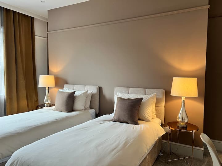 This bedroom looks onto Market Street through large double windows and will be made up as Twin singles unless you request Superking. Simple cotton bedding, a mixture of 'feels like down' and duck down pillows. Dresser, chair, hidden wardrobes.