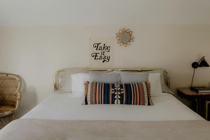 พื้นที่ขนาดใหญ่พร้อมเตียงคิงไซส์ โต๊ะข้างพร้อมโคมไฟอ่านหนังสือ และตู้เสื้อผ้าขนาดใหญ่ 