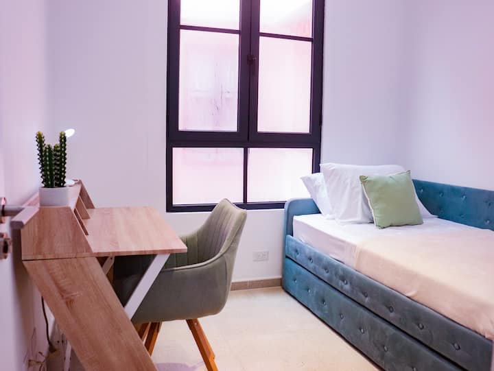Secondary room for two (2) people with a trundle bed with two twin/single size mattresses. This space is ideal if you also want to work from home as it has a desk, chair, AC and blackout curtains.