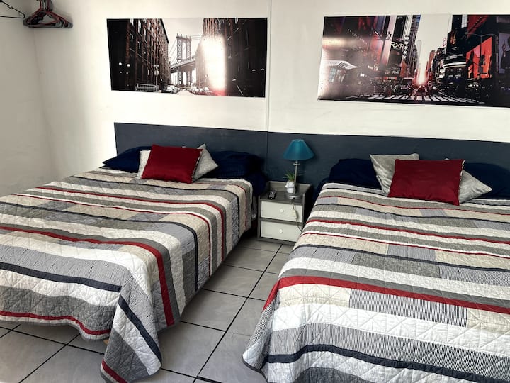 חדר מרווח עם שתי מיטות זוגיות, טלוויזיה וארון, חדר רחצה מחוץ לחדר.