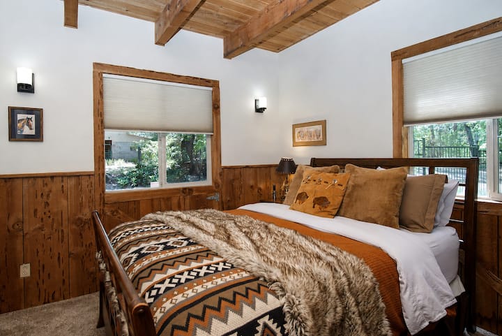 Settle into The Prairie Bison Room. Featuring beautiful wood wainscoting, vaulted ceilings with exposed beams, and wrap-around forest views, this cozy sanctuary blends authentic Western charm with ultimate comfort. Your perfect peaceful escape.