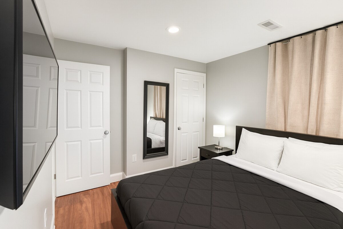 ห้องนอนที่น่าอยู่นี้มีเตียงขนาดควีนไซส์ทีวีจอแบนม่านทึบแสงโต๊ะข้างกระจกที่มีแสงสว่างเพียงพอความสามารถในการชาร์จ USB โคมไฟและตู้เสื้อผ้าขนาดพอเหมาะเพื่อรองรับทุกความต้องการในการจัดเก็บของคุณ