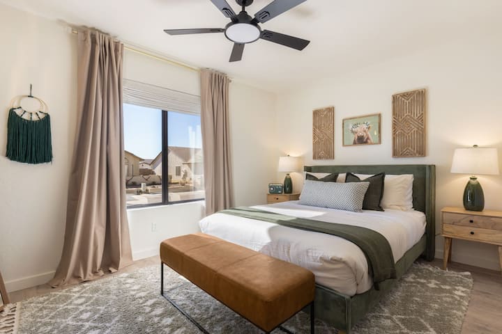 Pohodlná manželská posteľ s tmavými žalúziami a závesmi.