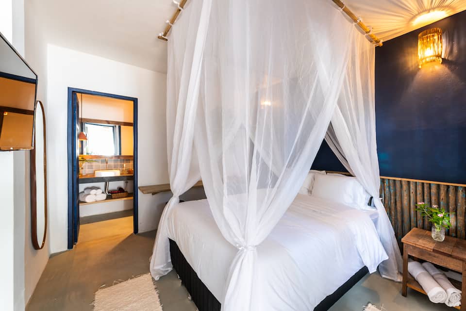 Suíte térrea com cama com dossel e parede azul