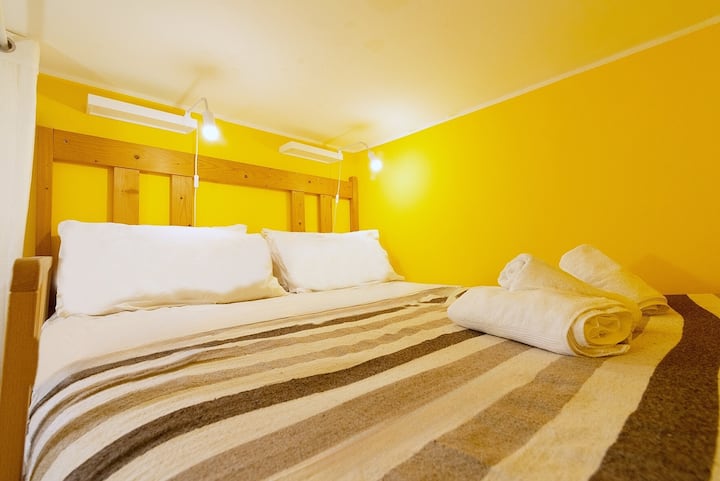 Doppelbett auf dem Dachboden, mit weicher Matratze, warmem Licht und Nesteffekt mit TV-Blick für totale und regenerierende Entspannung.

Doppelbett auf dem Zwischengeschoss mit weicher Matratze, warmem Licht und gemütlichem Nestgefühl für tiefe, erholsame Momente.