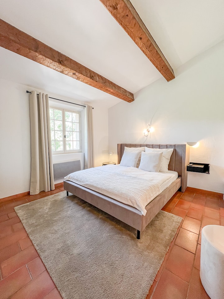 מיטה נוחה בגודל 180x200 המשקיפה על החצר עם עץ זית.