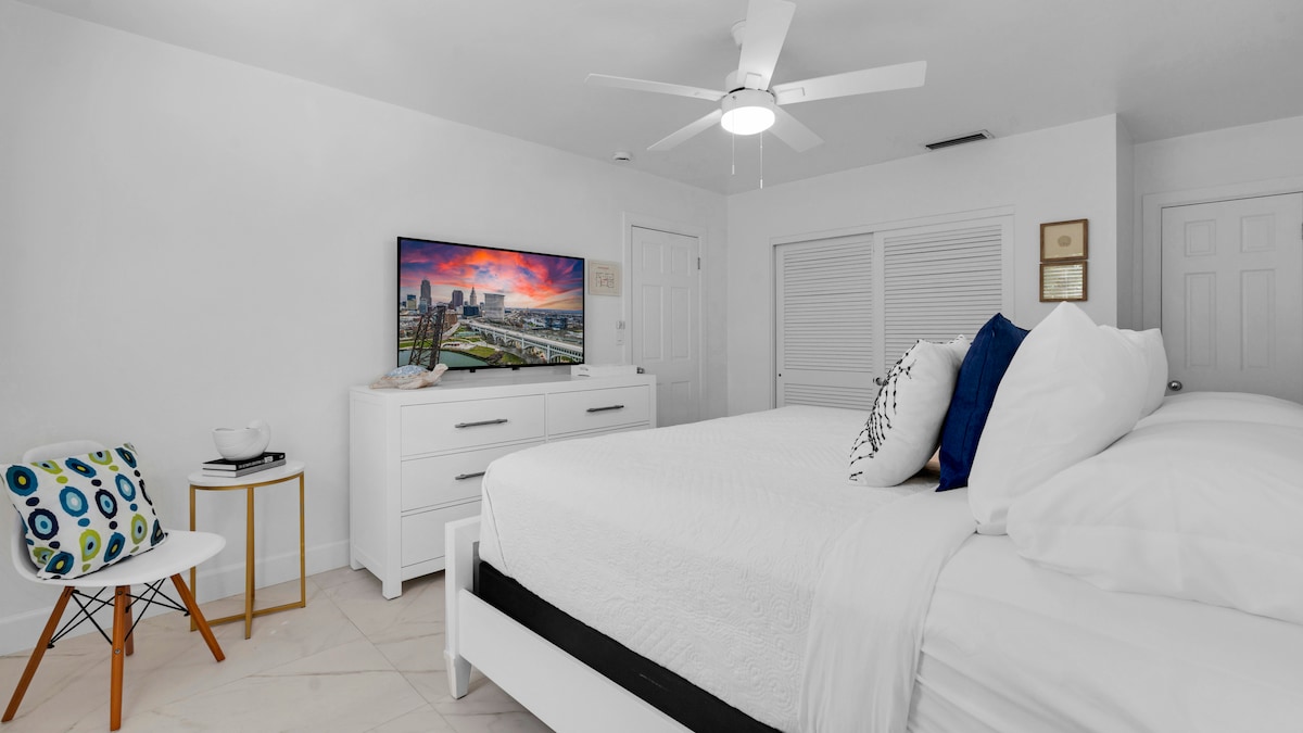 Dormitorio principal tamaño king con televisor inteligente de pantalla plana y ventilador de techo. El dormitorio tiene un baño privado con ducha a ras de suelo.  