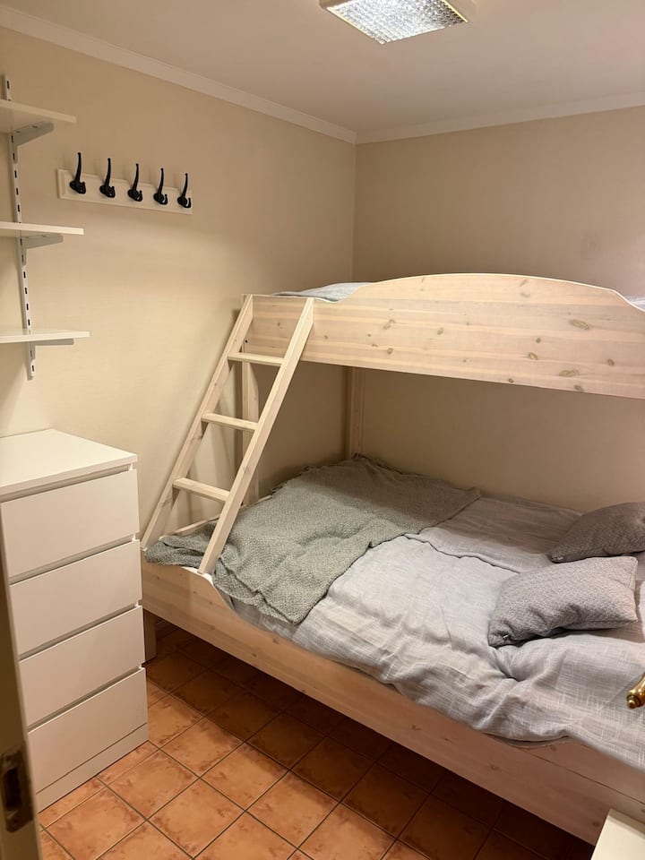 Долниот дел е широк 150 см, а горниот кревет широк 90 см. Во спалната соба 1 нема прозорци, но има светлина низ стаклото на вратата. Гардеробер, полици и куки за складирање облека и работи. 