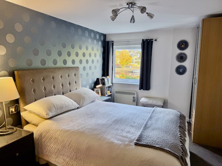 Moderná spálňa s manželskou posteľou, výraznou stenou, príjemným osvetlením a úložným priestorom. Ubytujte sa v krásnom byte v centre Yorku v blízkosti York Minster, The Shambles a butikov len pár minút odtiaľ.