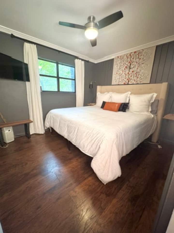 Štýlová druhá hlavná spálňa s televízorom Roku, svetlou a vzdušnou atmosférou a výhľadom na jazero.