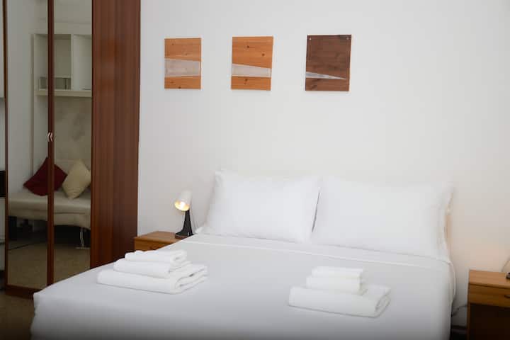 Druhá spálňa s manželskou posteľou Queen, plachtami prémiovej kvality a stenou zdobenou v teplých tónoch. Jednoduché a čisté pohodlie.