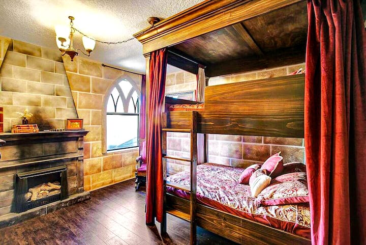 Brave enough to sleep in Gryffindor tower? Stone hearth, crimson curtains, a patterned quilt on the carved bunk bed. The High Castle Suite sleeps four behind fortress walls.