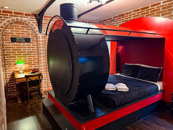 ✨ Grand Platform Suite: Step into a whimsical locomotive-themed master suite featuring a custom engine bed with a working steam stack, brick station walls, and atmospheric lighting.