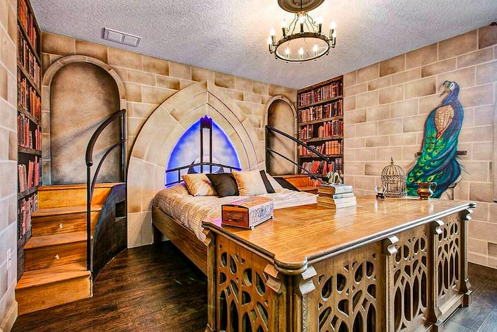 ✨ Details That Transport You: Step into a storybook headmaster’s office–inspired space filled with magical artifacts, warm ambient lighting, and floor-to-ceiling library décor.