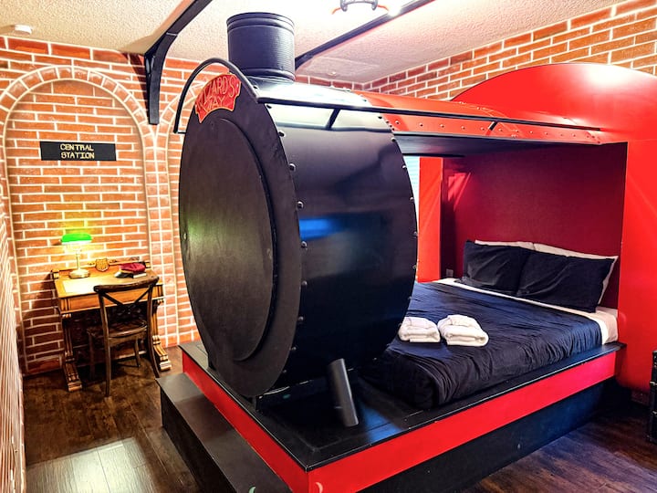 Climb aboard the Platform 9¾ locomotive bed. One button — steam billows, horn blows, station humming all around. Vintage trunks by the window, an 1800s desk tucked in a brick archway. The Grand Platform Suite sleeps two in style.