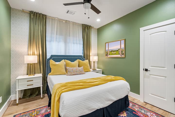 装饰精美的客卧，配备标准双人床、立式镜子、智能电视和衣柜。