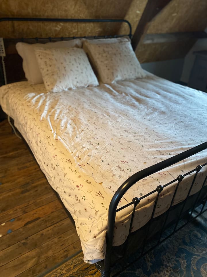 A charming bedroom on the first floor, the old trusses from 1900 are still visible. A double bed and a bedstead, scent of old wood, the serene silence of the tree nurseries, soft light through the windows, rustic and romantic atmosphere