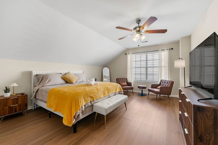 ห้องนอนใหญ่กว้างขวางพร้อมเตียงคิงไซส์ พัดลมติดเพดาน และแสงธรรมชาติ ออกแบบมาเพื่อความสะดวกสบายและผ่อนคลายด้วยการตกแต่งที่ทันสมัยและอบอุ่นสบาย