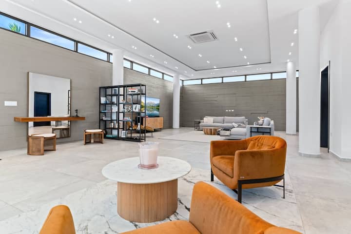 Táto veľkolepá obývacia izba, priestranná a elegantná, vás pozýva k štýlovému odpočinku. Vďaka elegantnému modernému dizajnu, mäkkým pohovkám a jemnému prirodzenému svetlu je to ideálne miesto na stretnutie, popíjanie vína alebo jednoducho na vychutnávanie si pokojnej atmosféry vily.