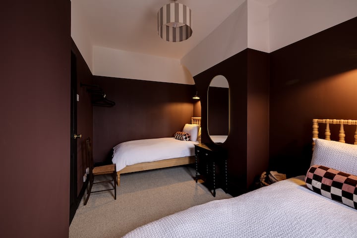 A cosy twin bedroom with rich tones, soft lighting and two comfortable beds — ideal for friends, colleagues or families. Thoughtfully styled with warm textures and a relaxed, welcoming feel. Perfect for longer stays in Chester.