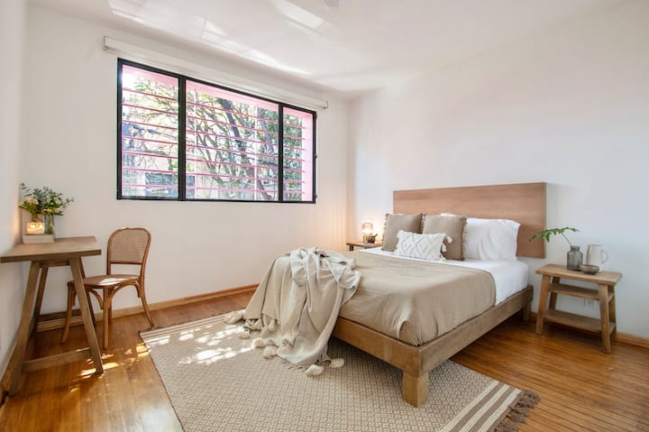 Მშვიდი საძინებელი ბუნებრივ სინათლეზე, ხის თბილი ტონებითა და მინიმალისტური ავეჯით. Რბილი ქსოვილები და მიწიერი ფერები ქმნის მშვიდ დასვენებას, რომელიც კომფორტს არასტანდარტულ ელეგანტურობასთან ერწყმის.