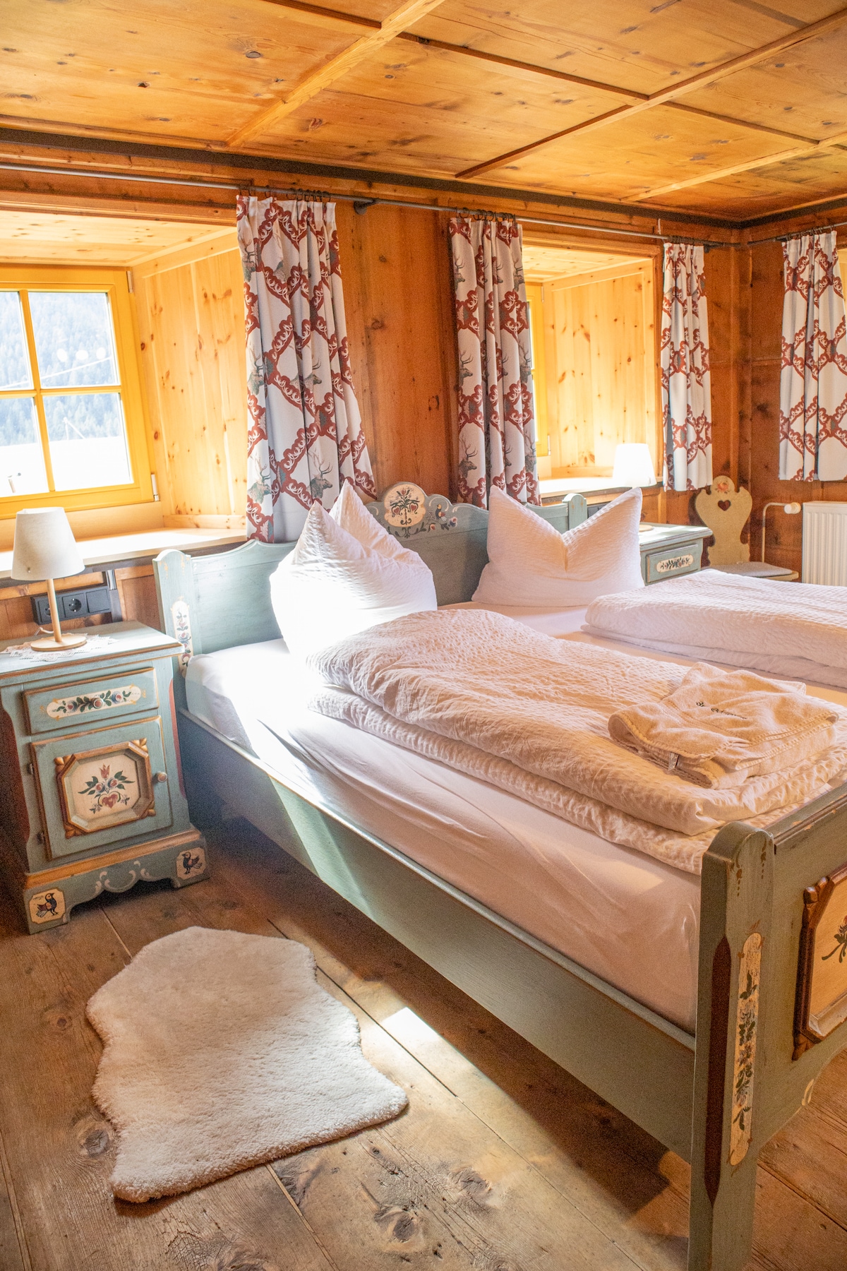 Amplia habitación doble con paredes de madera, armario tradicional y comodidad alpina. Cálido, acogedor y relajante.