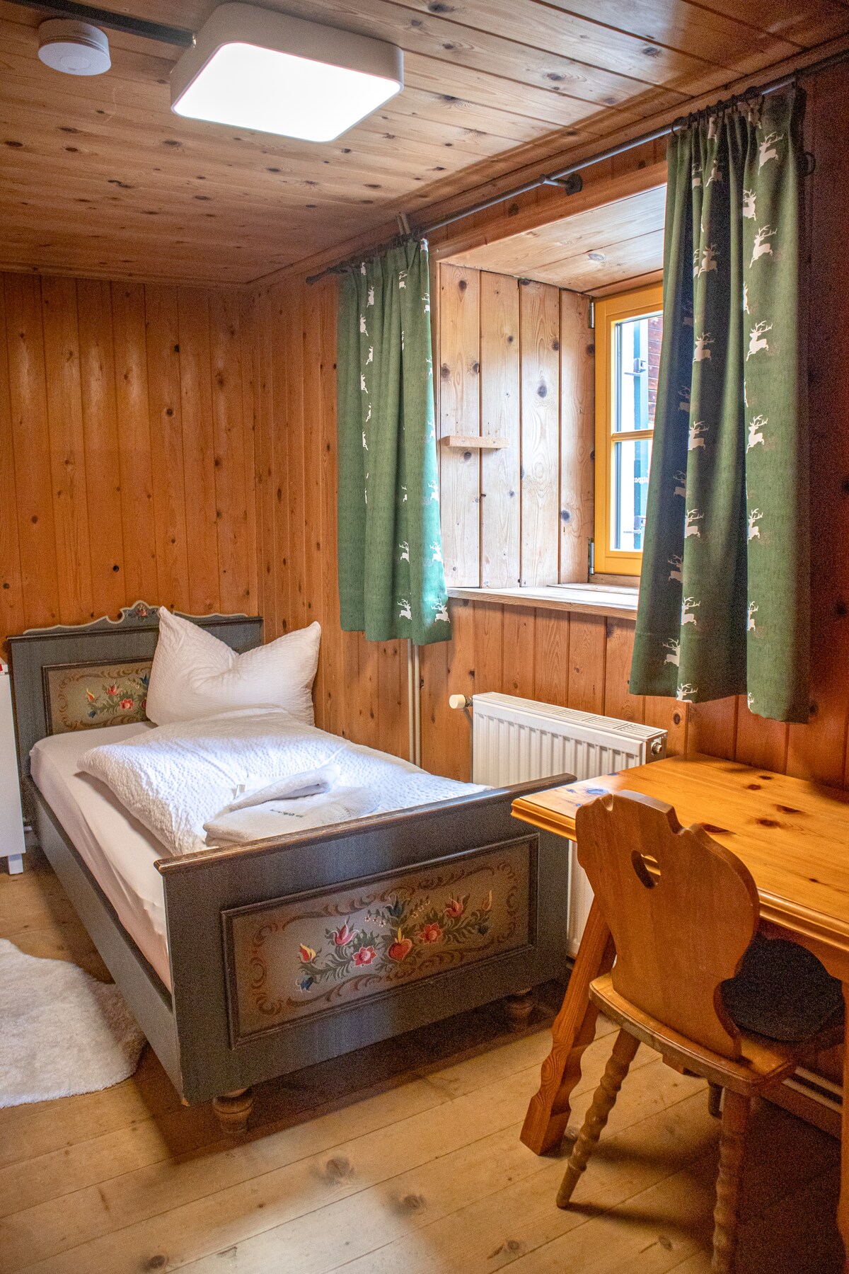 Habitación individual pequeña y rústica en el primer piso con paredes de madera y escritorio. Ideal para la tranquilidad y la recreación