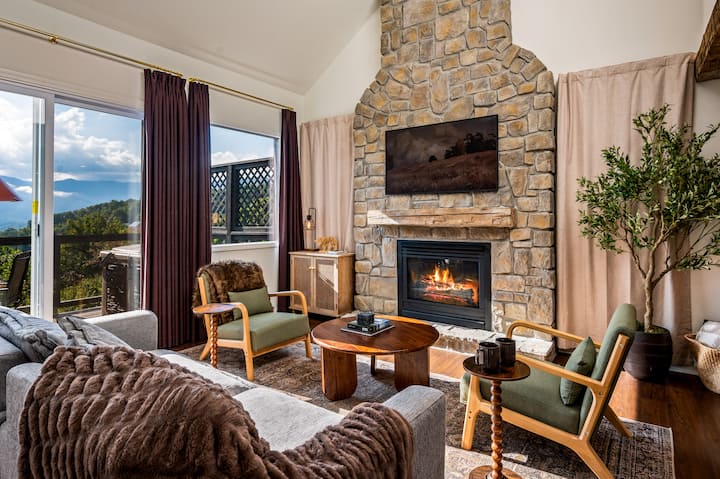 Sunlight pours through the open windows, filling the cozy mountain living room with warmth and the scent of pine.

