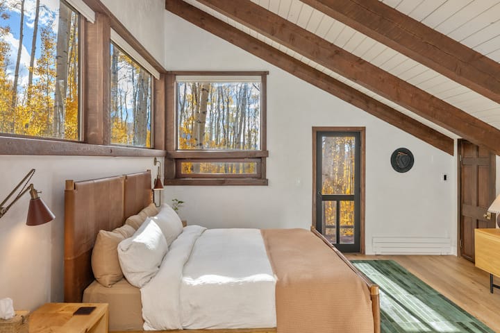 Primary Suite (upper level) — king with a pillow-top mattress, vaulted ceilings, lounge chair, private balcony, and a spa bath. Air purifier and humidifier.