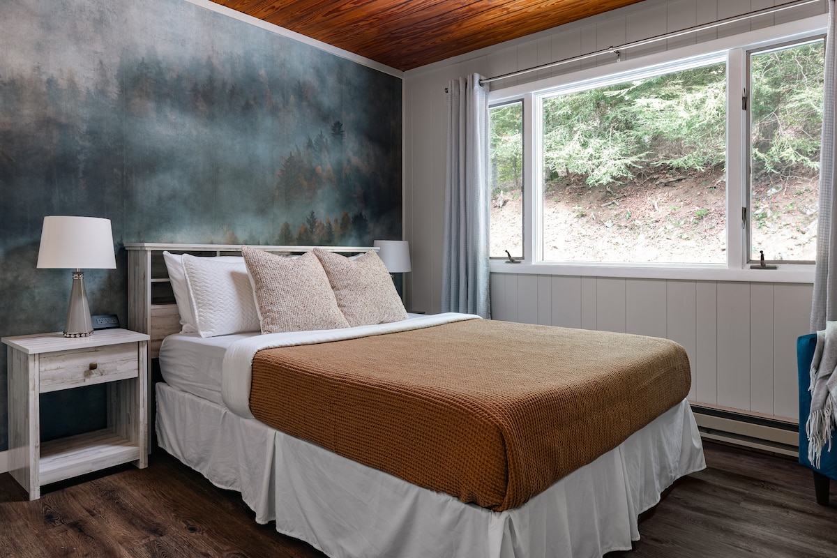 Dormitorio tamaño queen con ropa de cama de algodón afelpado y luz natural cálida inspirada en la montaña.